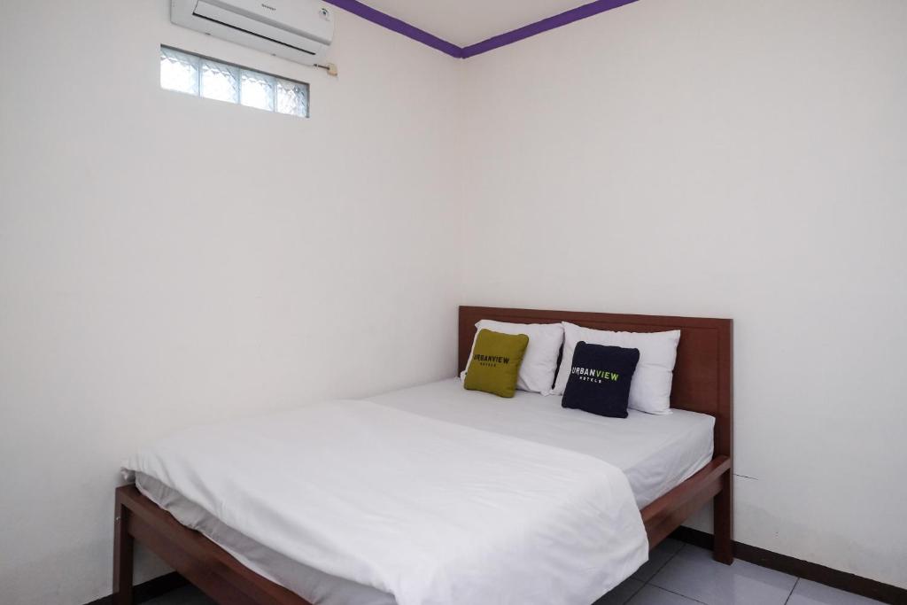 a bedroom with a bed with white sheets and pillows at Urbanview Syariah Zidney 3 Salatiga by RedDoorz in Salatiga