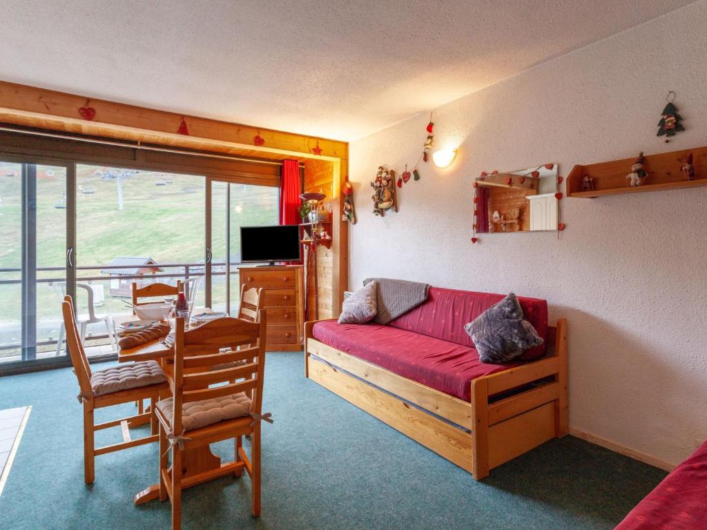 een woonkamer met een rode bank en een tafel bij Apartment Baikonour-4 by Interhome in Le Corbier