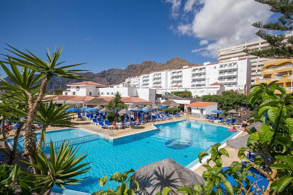 a large swimming pool with chairs and a hotel at Ona el Marqués in Puerto de Santiago