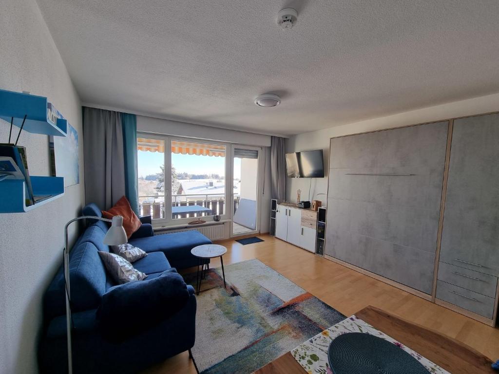 Apartment Alpensicht by Interhome في هوتشنشوند: غرفة معيشة مع أريكة زرقاء وطاولة