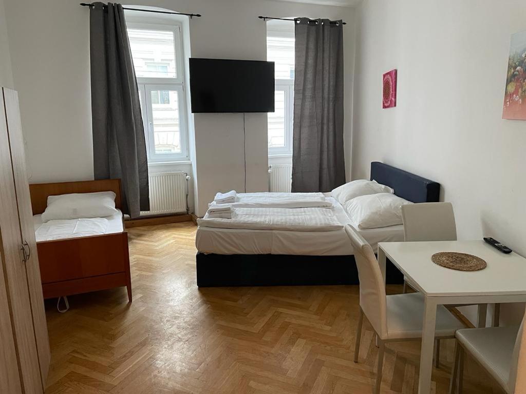 ein kleines Zimmer mit 2 Betten, einem Tisch und einem sidx sidx in der Unterkunft easybook-in in Wien