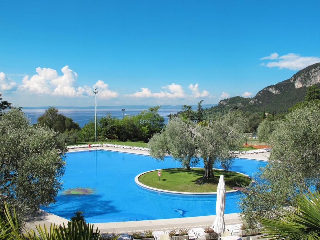 a swimming pool with a tree and an umbrella at Apartment Parco del Garda-4 by Interhome in Garda