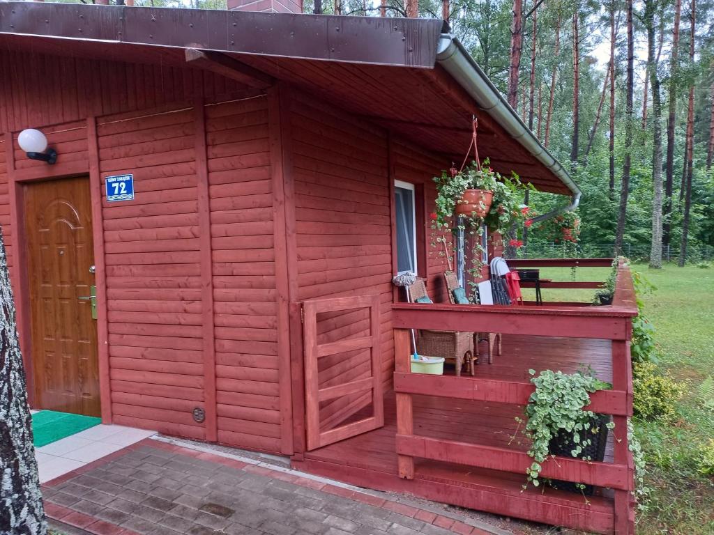 einen roten Schuppen mit einer Tür und einer Veranda in der Unterkunft Domek letniskowy nad jeziorem w Gołdapi, Wczasowa72 in Goldap