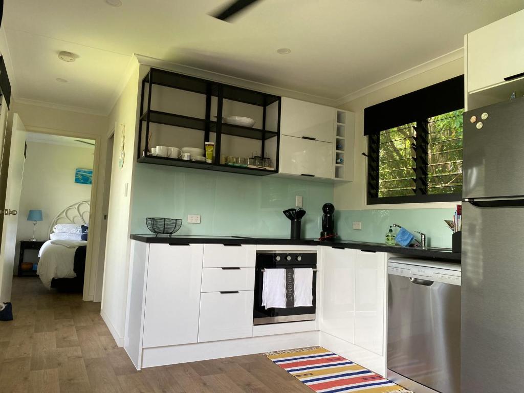 a kitchen with white cabinets and a stove at Haven Guesthouse in Holloways Beach