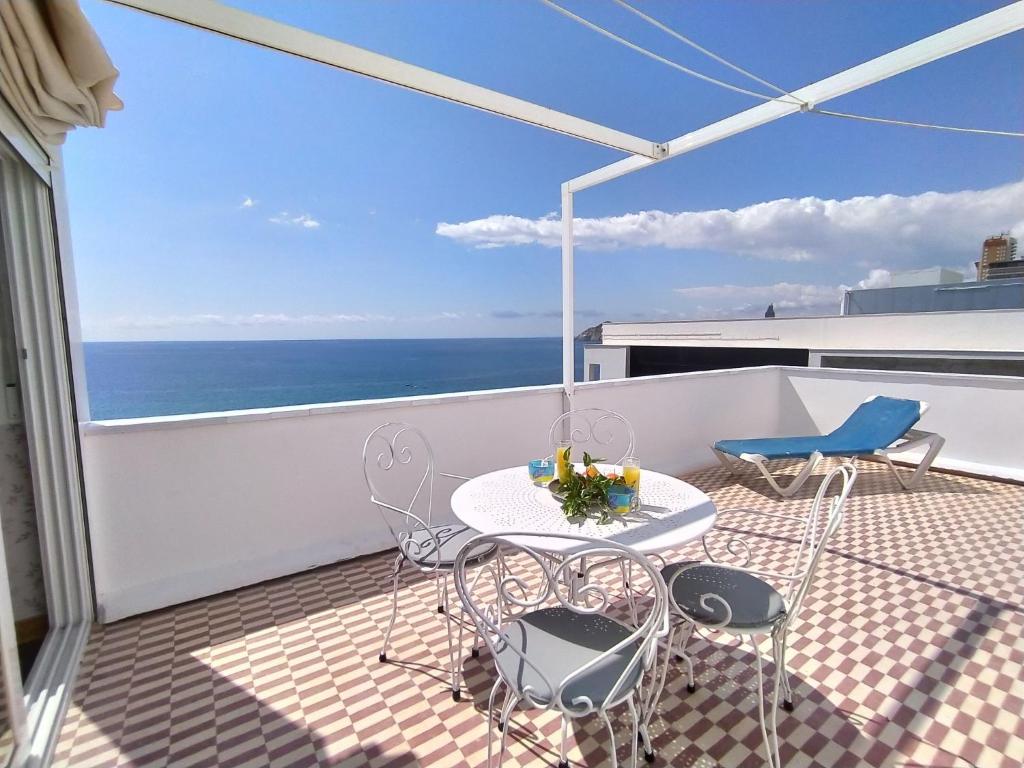 een balkon met een tafel en stoelen en de oceaan bij Apartment Suecia by Interhome in Benidorm