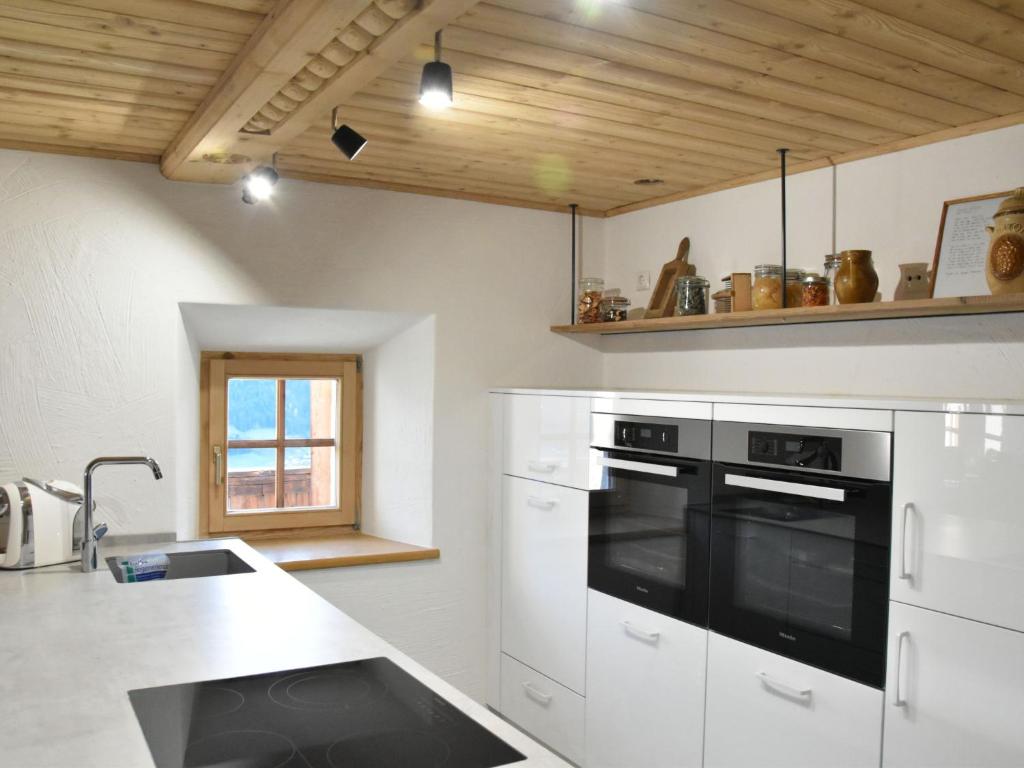 a kitchen with white cabinets and a black oven at Apartment Appartment Wiesberg by Interhome in Niedernsill