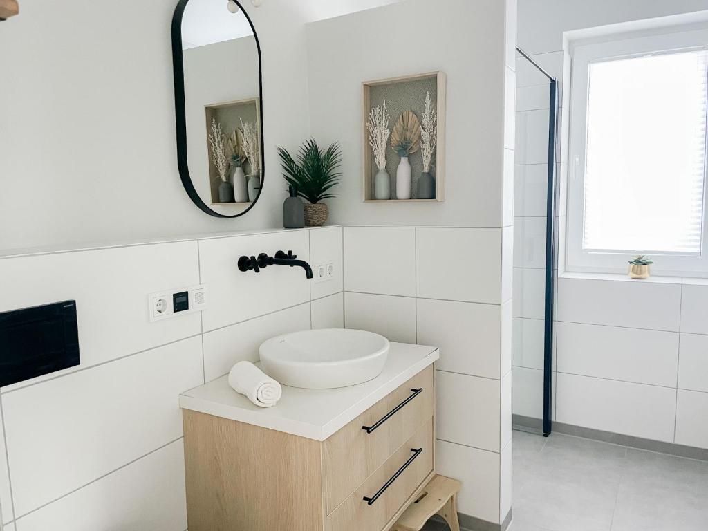 ein weißes Badezimmer mit einem Waschbecken und einem Spiegel in der Unterkunft Ferienwohnung Baltic Idyll in Scharbeutz
