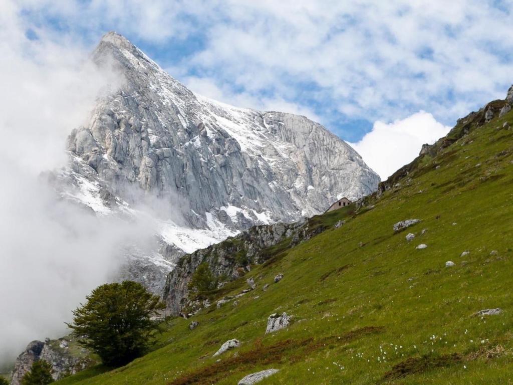 a snow covered mountain on top of a green hill at Apartment La Collina by Interhome in Rivisondoli