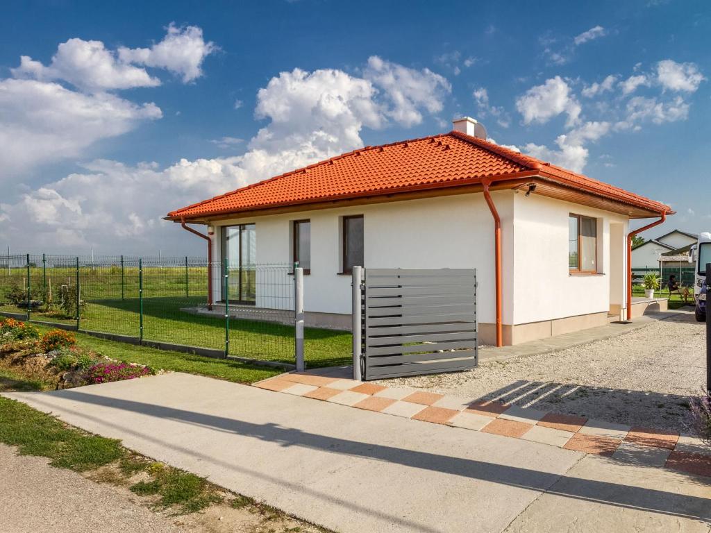 una pequeña casa blanca con techo naranja en Holiday Home Emily by Interhome, en Csisztapuszta