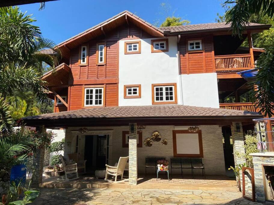 een groot houten huis met een veranda en stoelen bij Hermosa villa en Jarabacoa in Jarabacoa