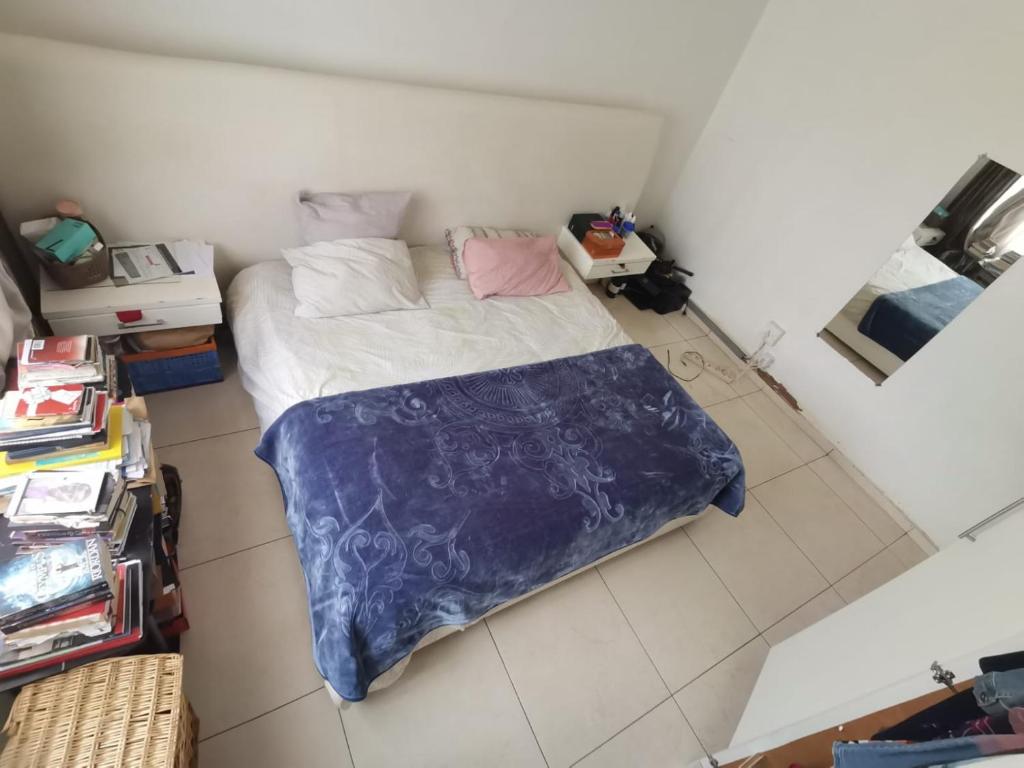 een kleine slaapkamer met een bed met een blauwe deken bij House n Car in Krugersdorp