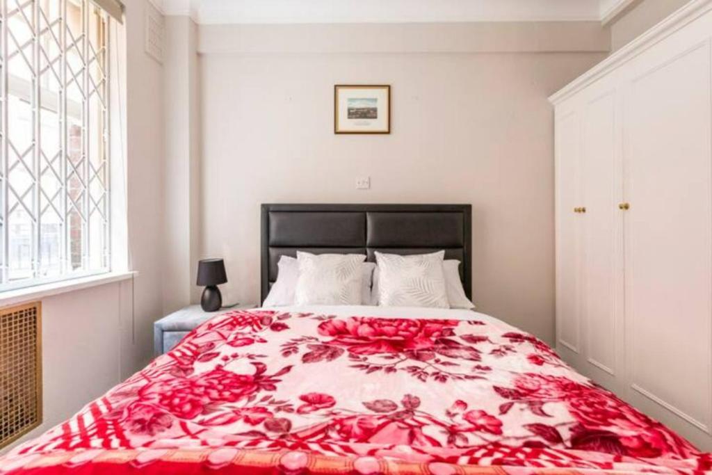 a bedroom with a large bed with a red blanket at Great Mayfair London Flat in London