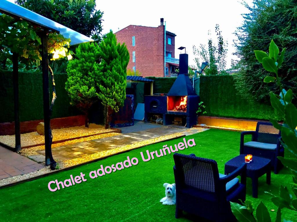 un patio con césped con chimenea y un perro en CHALET ADOSADO CON GARAGE Y TERRENO, en Uruñuela