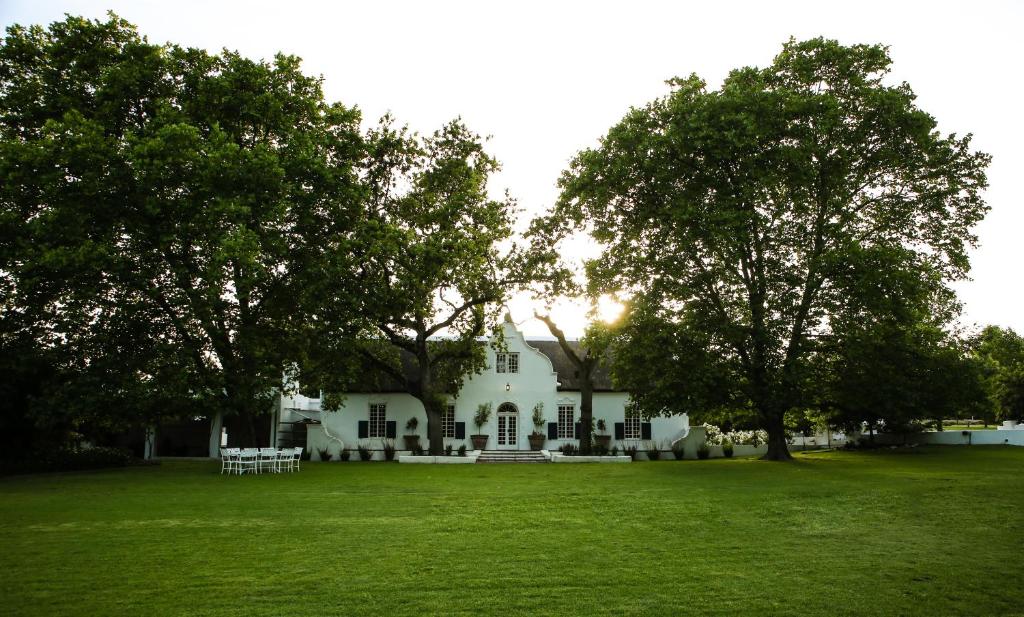 una casa bianca con degli alberi di fronte di San Gabriel Homestead a Somerset West