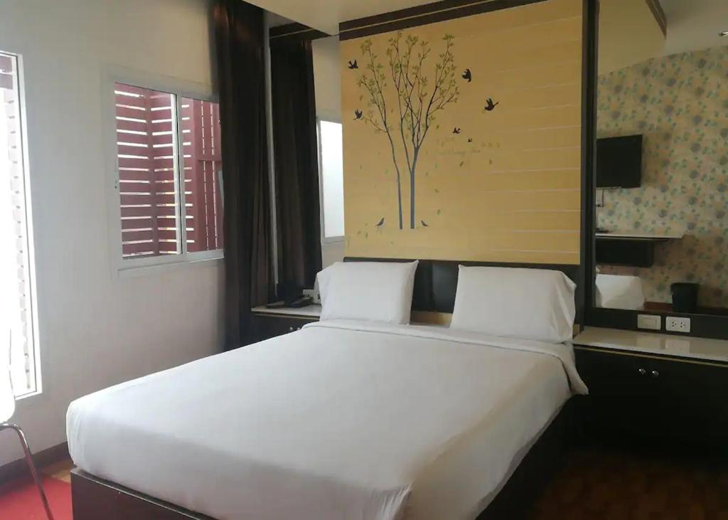 een slaapkamer met een groot wit bed in een kamer bij The Ring Khokmao Hotel 