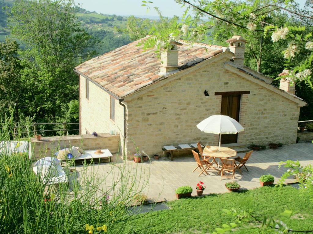 a small stone house with a table and an umbrella at Charming Villa in Monte San Martino with Swimming Pool in Monte San Martino