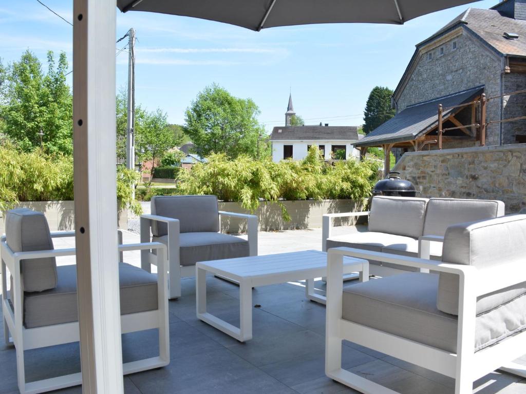 d'une terrasse avec des tables et des chaises blanches et un parasol. dans l'établissement Cozy Holiday Home in Gedinne near Forest, à Vencimont