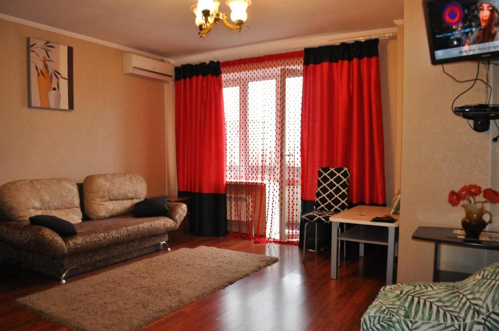 sala de estar con sofá y cortinas rojas en Spacious apartment with balcony, en Kremenchuk