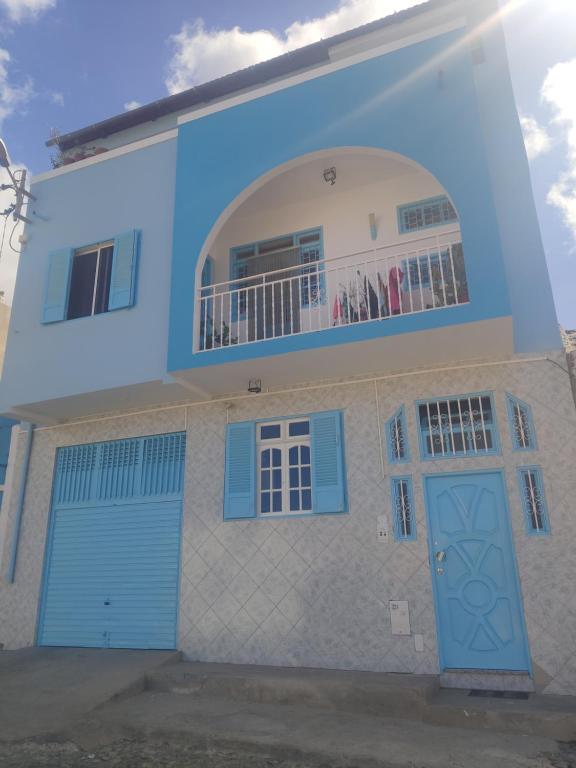 uma casa com portas azuis e uma varanda em Maderalzinho em Mindelo