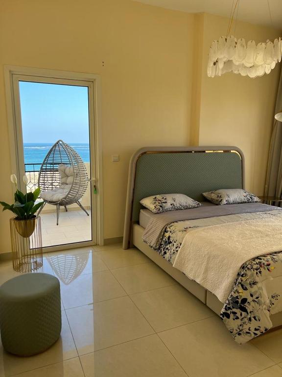 a bedroom with a bed and a patio with a chair at Royal Breeze view in Ras al Khaimah