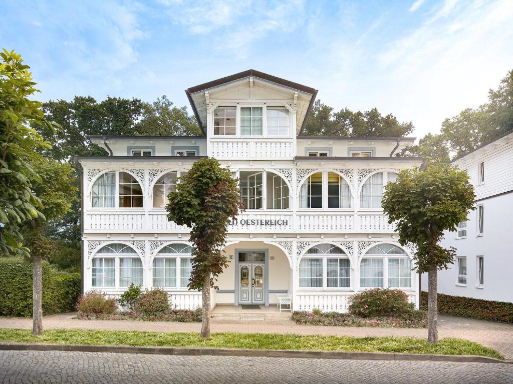 une maison blanche avec des arbres devant elle dans l'établissement Villa Oestereich, à Binz