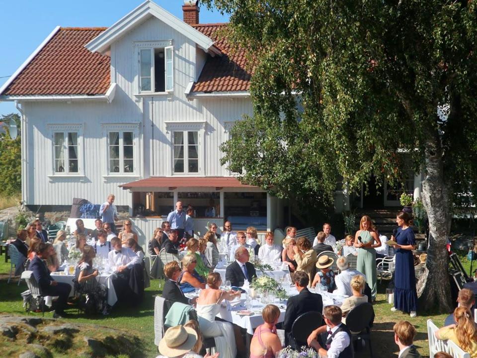 Un groupe de personnes assises à des tables devant une maison dans l'établissement Portør Pensjonat, à Kragerø