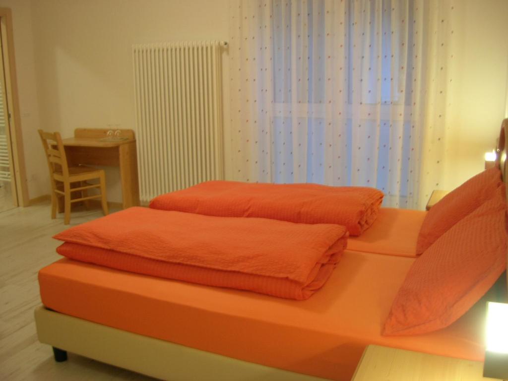 un letto con lenzuola arancioni sopra in una stanza di Agriturismo La Decima a Trento