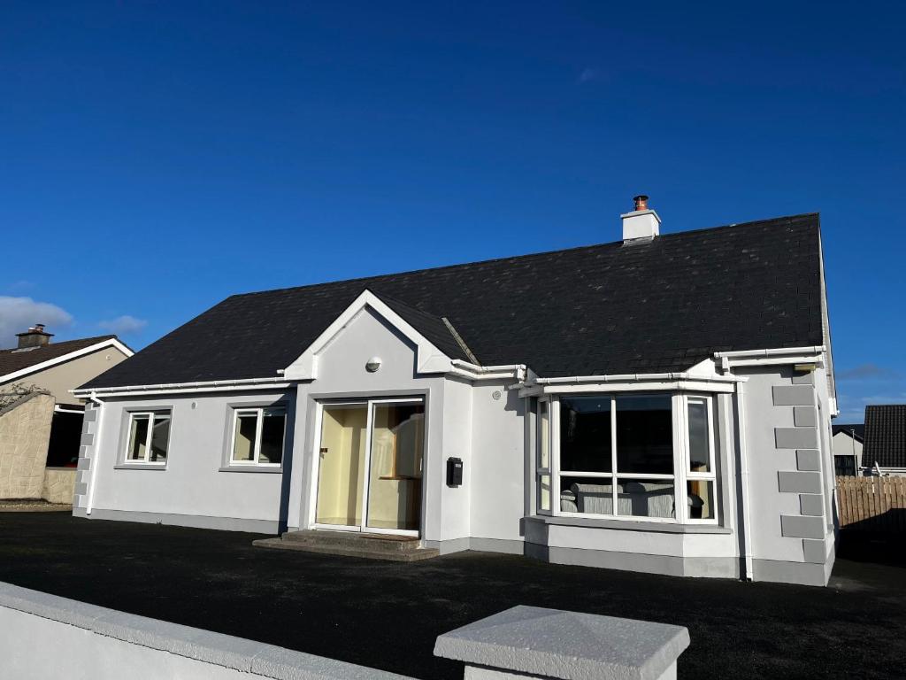 een wit huis met een zwart dak bij Ashdoon House in Donegal