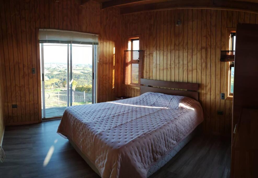 1 dormitorio con cama y ventana grande en Agradable y cómoda cabaña con vista espectacular, en Chonchi