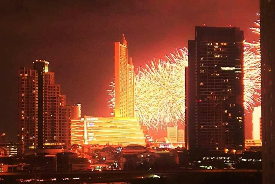 un feu d'artifice dans une ville abritant de grands bâtiments dans l'établissement The Cosy River, à Bangkok