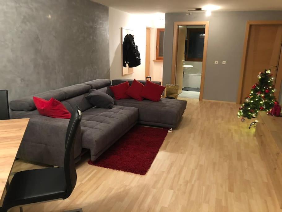a living room with a gray couch and a christmas tree at Appartamento nuovo e comfort a Brunico Kronplatz in Brunico