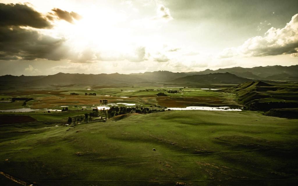 a view of a golf course with mountains in the background at Penwarn Farm Lodge in Drakensberg Garden