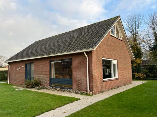 a red brick house with a gambrel roof at Jadi in Cadzand