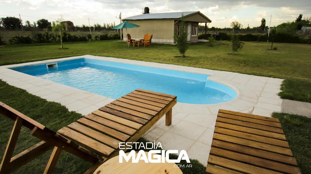 una piscina con dos bancos y una mesa y una casa en Quinta Aires en San Rafael