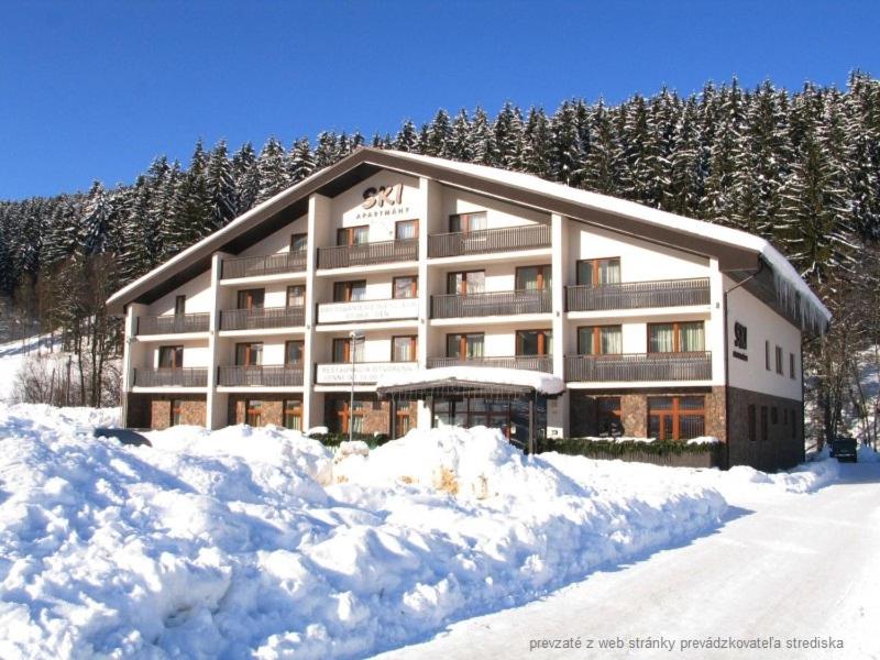 a large building with snow in front of it at Ski Apartmán Sajmon so saunou in Makov