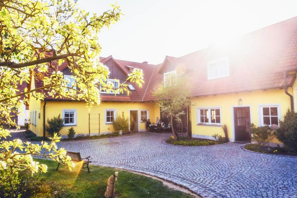 a large yellow house with a stone driveway at Pension Sankt Urban in Sommerach