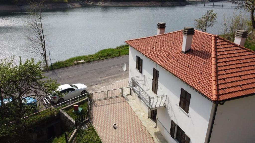 una casa bianca con un'auto parcheggiata accanto all'acqua di La Casa Sul Lago a Osiglia