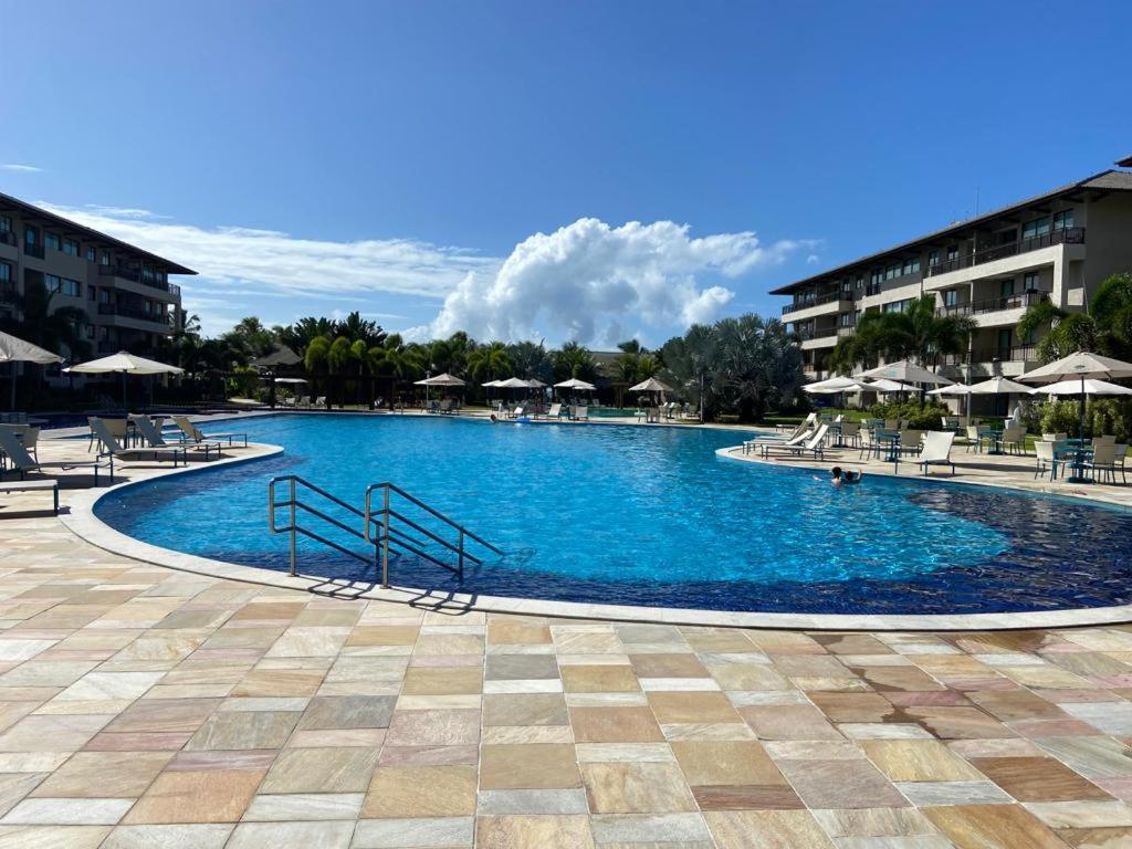 ein großer Swimmingpool mit Liegen und Sonnenschirmen in der Unterkunft Muro alto Bangalô beach class ecolife in Porto De Galinhas