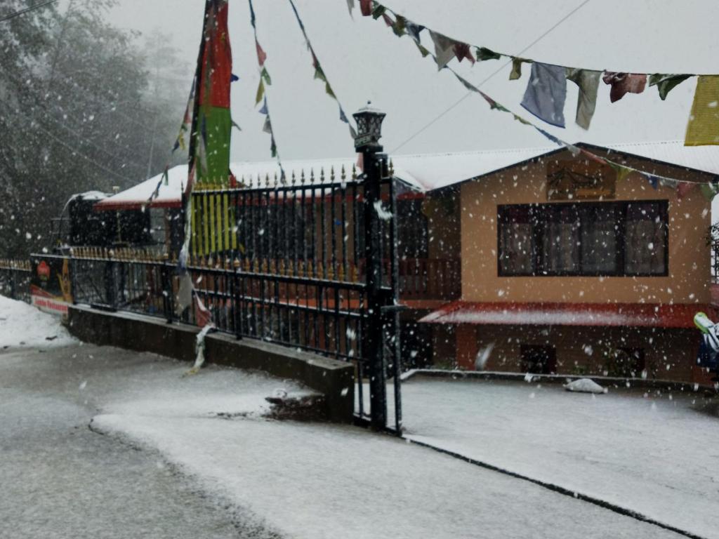 a snow covered street with a building and a fence at Gombo Hideaway in Nagarkot
