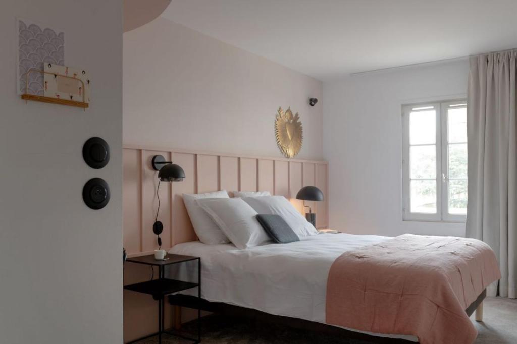 a white bedroom with a large bed and a window at Hôtel Le Prieuré in Paray-le-Monial