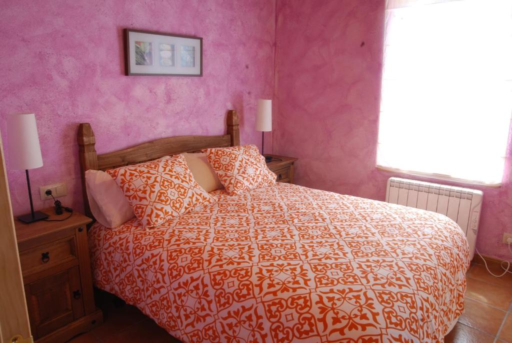 a bedroom with a bed and a pink wall at La formigana in Soto y Amío