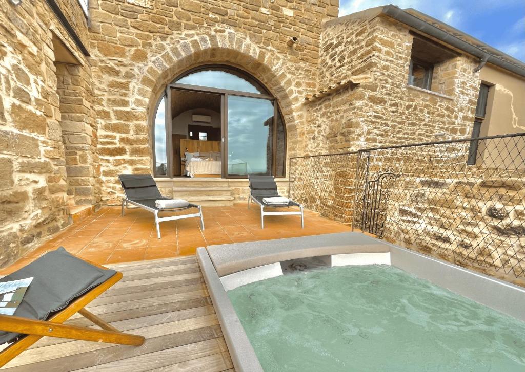 un patio con bañera de hidromasaje en un edificio de ladrillo en Torre Medieval de Queralt y Spa, en Concabella