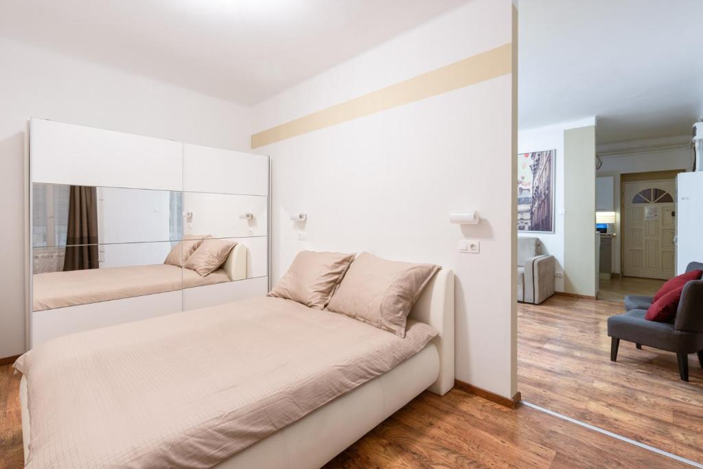 a white bedroom with a bed and a mirror at Central Seven Erzsebet Krt in Budapest