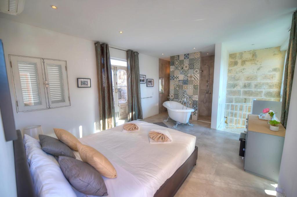 een slaapkamer met een groot bed en een bad bij Casa Bartolo A Hidden Gem - Spacious Village Home EBAR1-1 in Lija