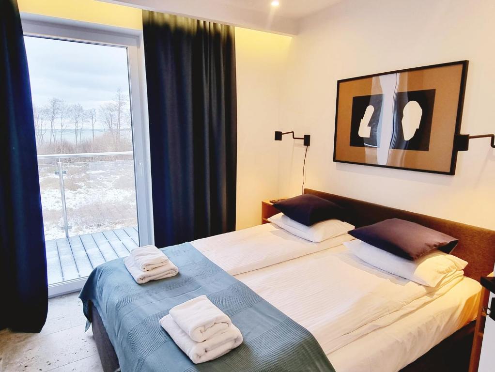 - 2 lits dans une chambre avec une grande fenêtre dans l'établissement Apartament Bliżej Morza w Gąskach - 365PAM, à Gąski