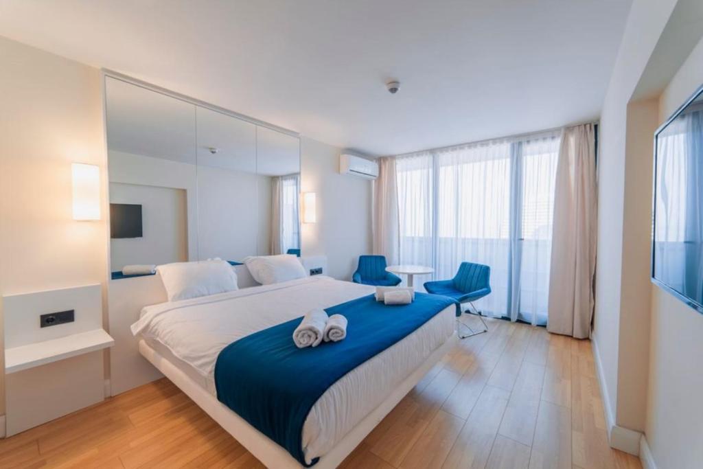 een slaapkamer met een groot bed en 2 blauwe stoelen bij Orbi City Sea View in Batoemi