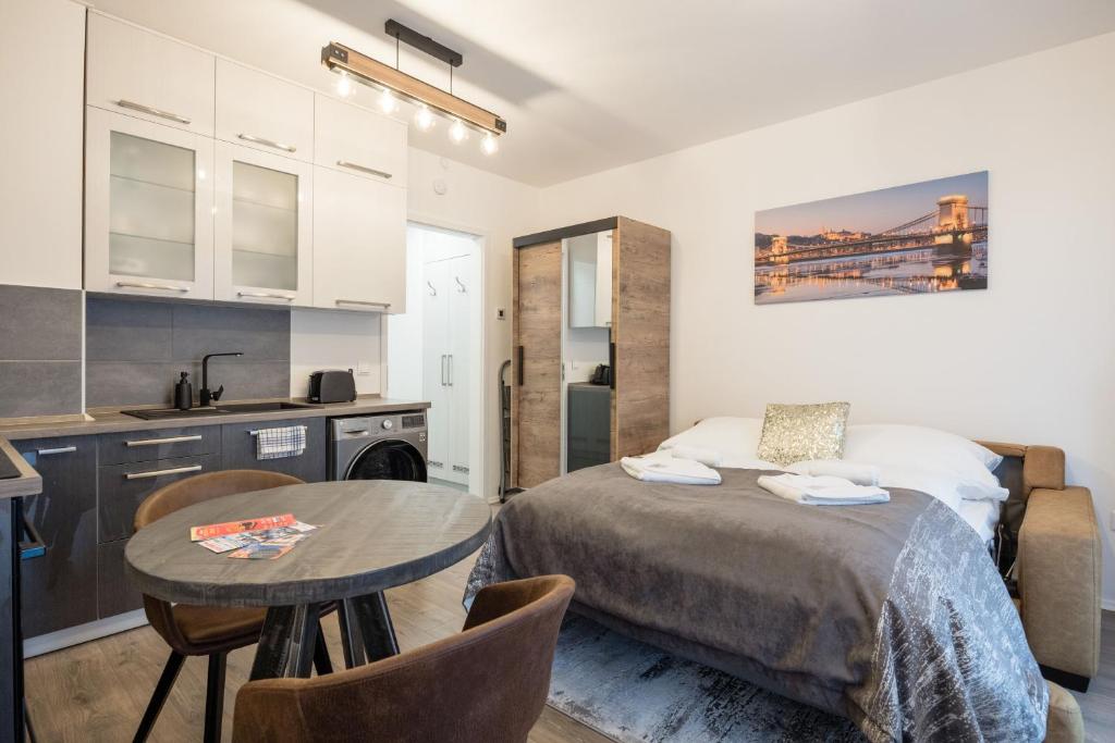 a bedroom with a bed and a table and a kitchen at Central Sphere Apartment in Budapest