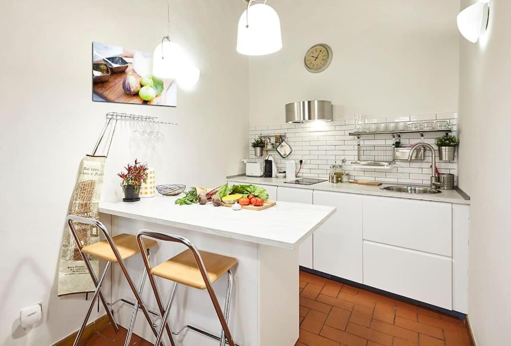 eine Küche mit weißen Schränken und einem Tisch mit einer Schale Obst in der Unterkunft Sant'Ambrogio Studio in Florenz