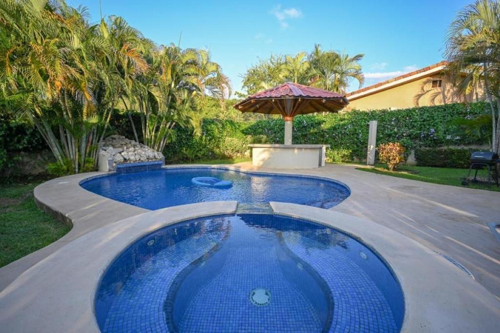 una piscina en un patio con sombrilla en Altos del Flamingo 38- 3BR House with Pool, en Playa Flamingo