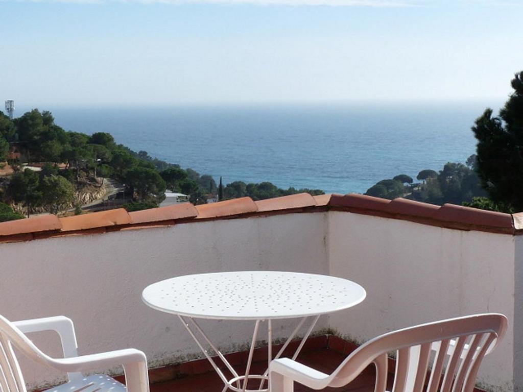 una mesa blanca y sillas en un balcón con vistas al océano en Private Apartments Cala Canyelles, en Lloret de Mar